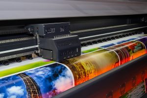 A colourful image is being printed from an industrial printer